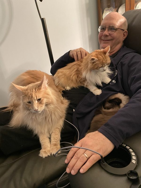 care partner | Pulmonary Fibrosis News | Kevin smiles while petting one of two adorable furry cats on his lap