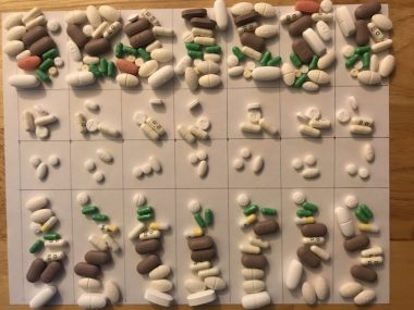 medication management | Pulmonary Fibrosis News | Numerous pills are laid out on a grid, with seven columns representing the days in a week, and four rows representing different times of day.