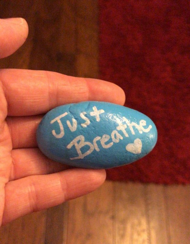 How to bring joy to others | Pulmonary Fibrosis News | Sam holds a rock painted sky blue with the words "Just Breathe" written in white, followed by a heart.