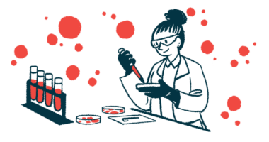 A scientist wearing gloves and safety goggles works with a petri dish in a lab alongside a rack of test tubes.