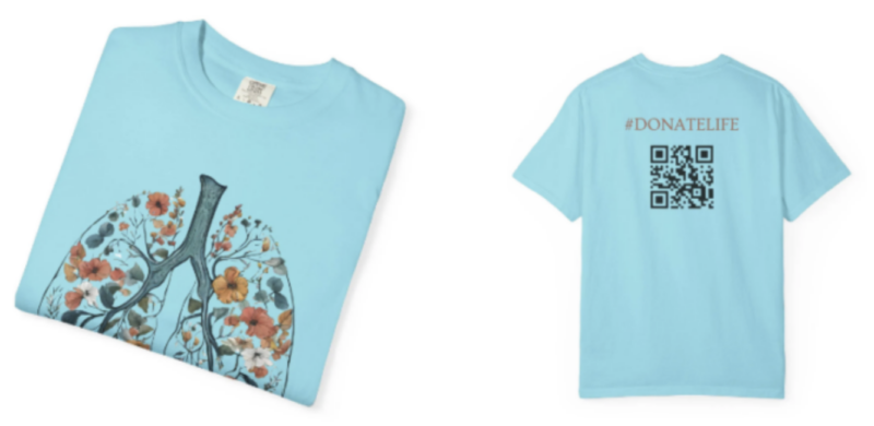 The front and back of a light blue T-shirt. The front shows a floral/tree design in the shape of lungs; the back shows a QR code and the hashtag #DonateLife